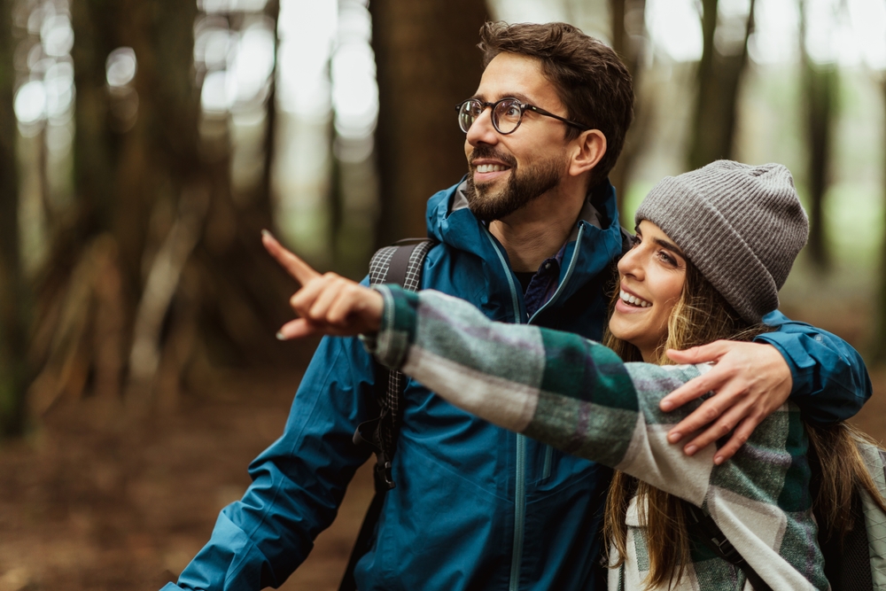 Glad,young,caucasian,couple,in,jackets,enjoy,journey,,points,finger